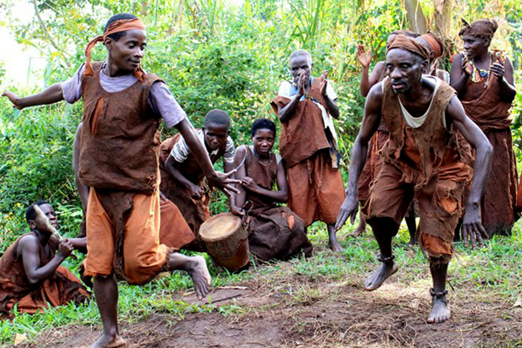 Batwa community members sharing music and dance beside a forest